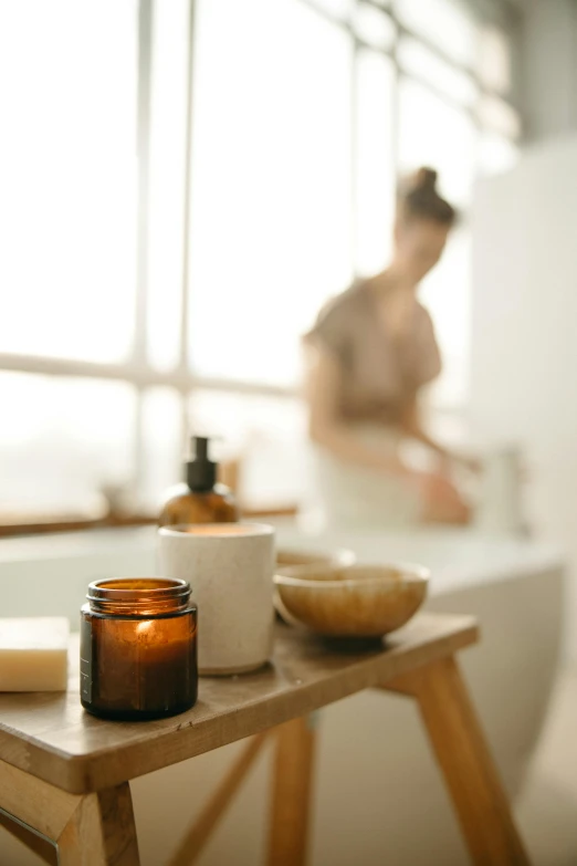 a woman standing in a bathroom next to a bath tub, trending on pexels, process art, jar on a shelf, natural materials, back lit, spa