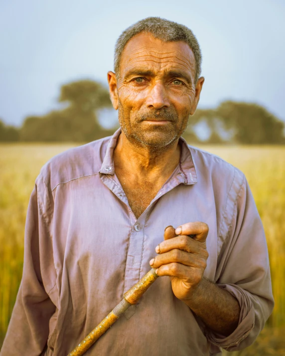 a man standing in a field holding a stick, inspired by Steve McCurry, pexels contest winner, renaissance, middle eastern skin, stubble, people at work, prideful look