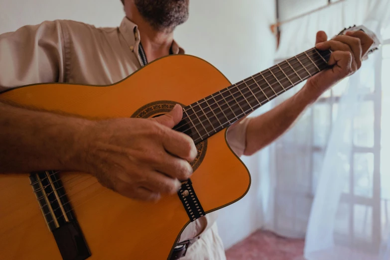 a man holding a guitar in front of a window, inspired by Agustín Fernández, pexels contest winner, traditional corsican, zoomed in, slightly tanned, ochre