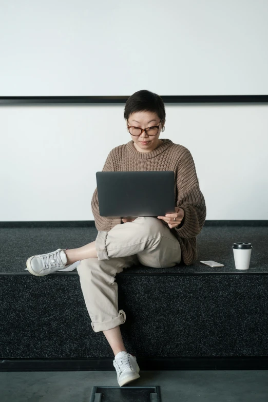 a woman sitting on a bench using a laptop, inspired by Fei Danxu, trending on unsplash, hypermodernism, sitting on the floor, taupe, nerdy appearance, asian male