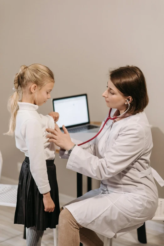a woman with a stethoscope sitting next to a little girl, pexels contest winner, incoherents, open v chest clothes, gif, low quality photo, no words 4 k