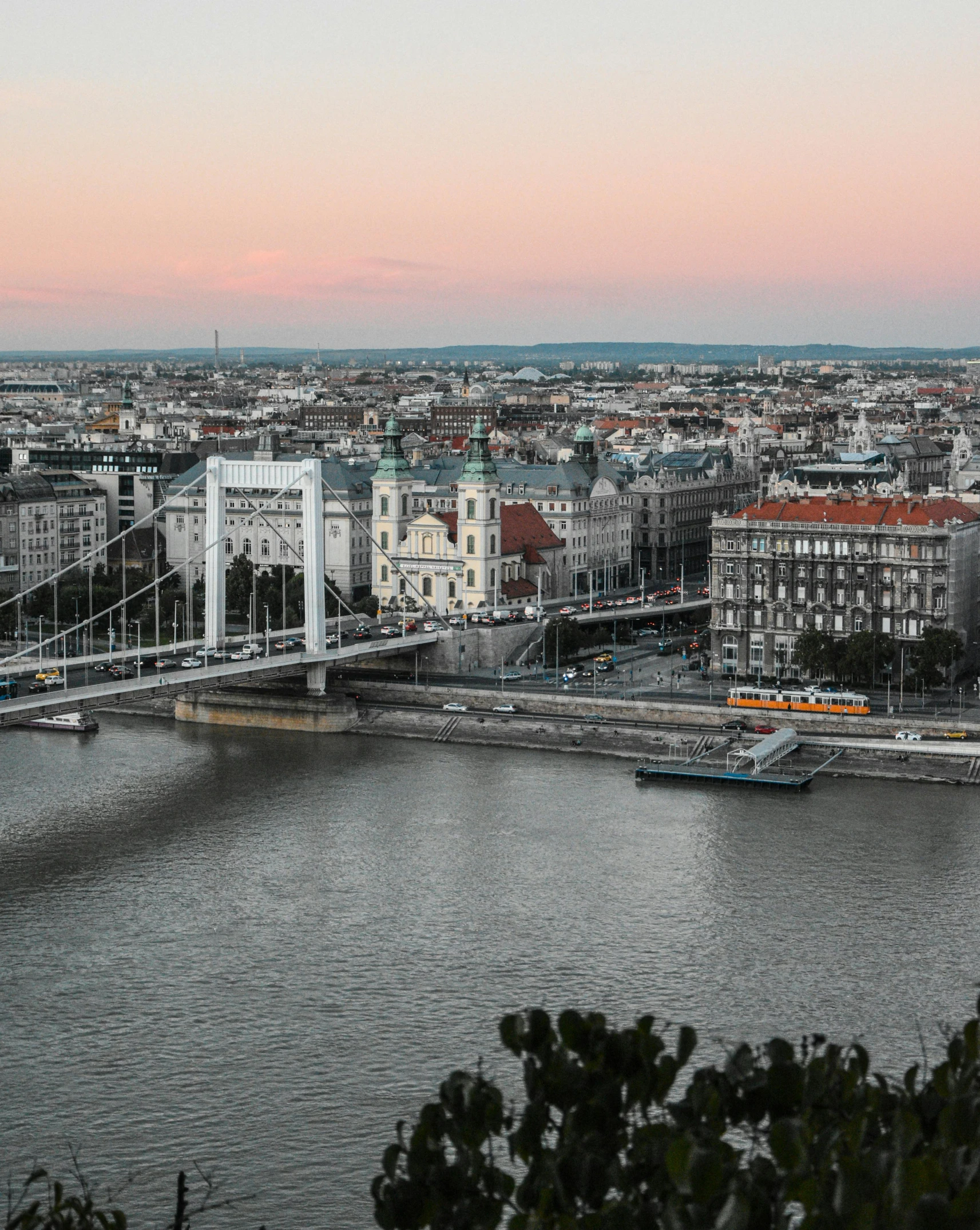 a view of a city from the top of a hill, by Matija Jama, pexels contest winner, viennese actionism, river in the background, bridge, hotel room, early evening