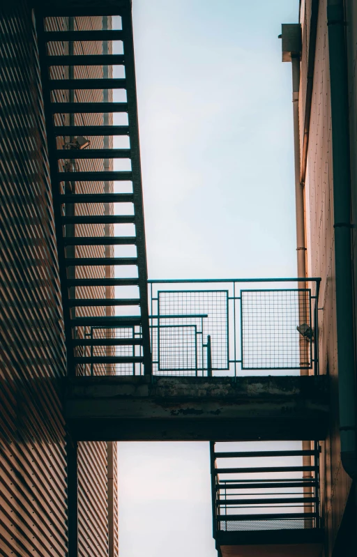 a couple of stairs going up the side of a building, a photo, unsplash, low quality photo, sky bridge, grid and web, back alley