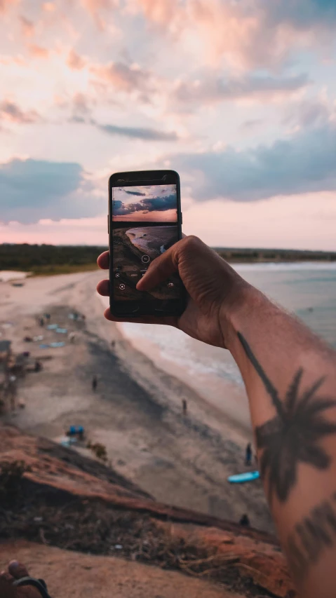 a person taking a picture of a beach at sunset, by Adam Rex, realism, tattooed, top down photo