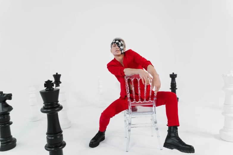 a man sitting on a chair surrounded by chess pieces, an album cover, by Julia Pishtar, pexels contest winner, red jumpsuit, arca album cover, posing like a knight, youtube thumbnail