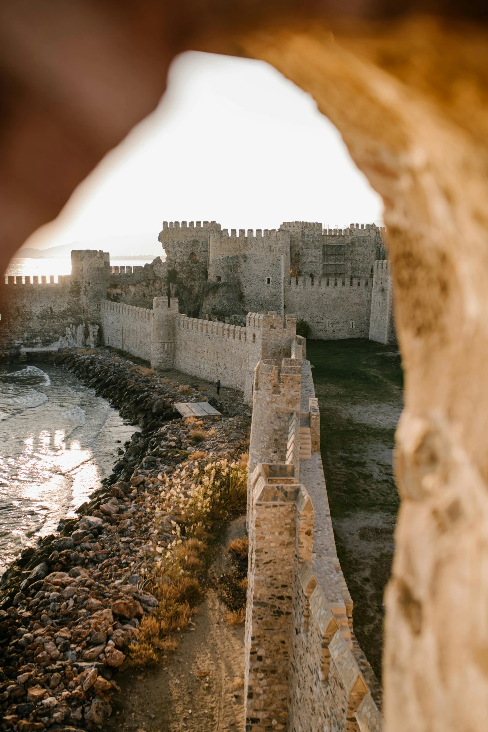 a view of a castle through a hole in a stone wall, pexels contest winner, renaissance, ottoman empire, wall of water either side, seaside, high angle shot