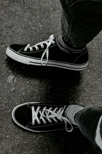 a black and white photo of a person standing on a skateboard, a black and white photo, trending on pexels, sots art, converse, black and silver, hot topic, plain background