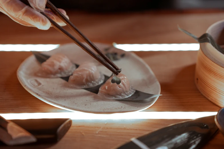 a person holding chopsticks over a plate of food, dumplings on a plate, sculpting, ukiyo, on a wooden table