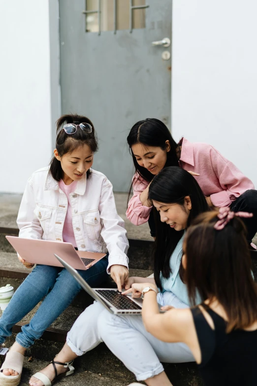 a group of women sitting on steps looking at a laptop, trending on pexels, young asian girl, teaching, splash image, schools