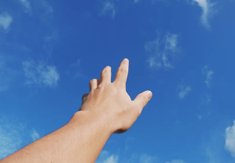 a person reaching up into the sky to catch a frisbee, trending on pexels, pointing index finger, cloudless blue sky, instagram post, unclipped fingernails