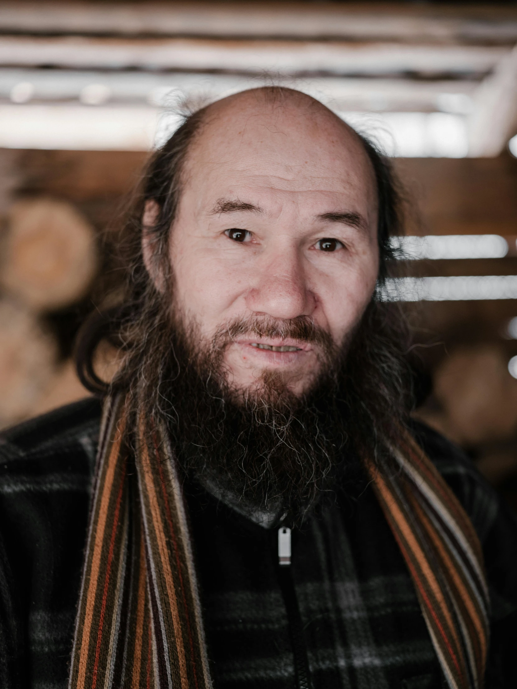 a man with a beard wearing a scarf, a portrait, inspired by Mikhail Evstafiev, unsplash, balding, lumberjack, mongolia, slightly smiling