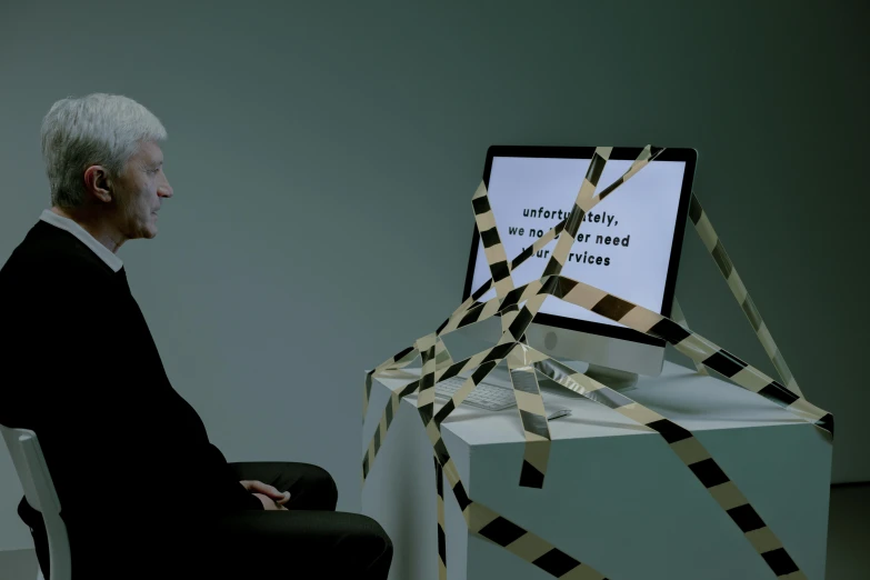 a man sitting in a chair in front of a computer, by Marina Abramović, unsplash, video art, ian mcdiarmid, a wooden, with screens and silks, david lynch