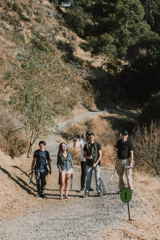 a group of people walking down a dirt road, an album cover, los angelos, ravine, drone photo, squad