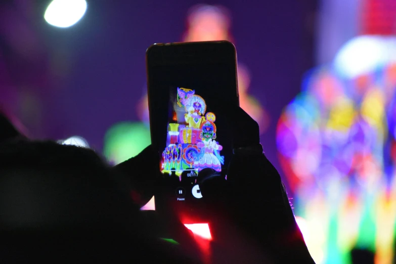 a person taking a picture with a cell phone, by Robbie Trevino, holography, scene from a rave, a brightly colored, performing, holiday season