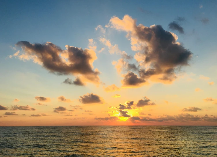 a view of the sun setting over the ocean, unsplash, romanticism, yellow clouds, varadero beach, sunset photo