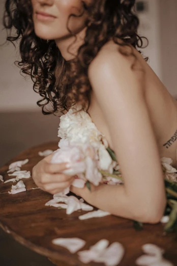 a beautiful woman laying on top of a wooden table, a tattoo, inspired by Elsa Bleda, trending on unsplash, made of flowers, curls, low quality photo, disrobed