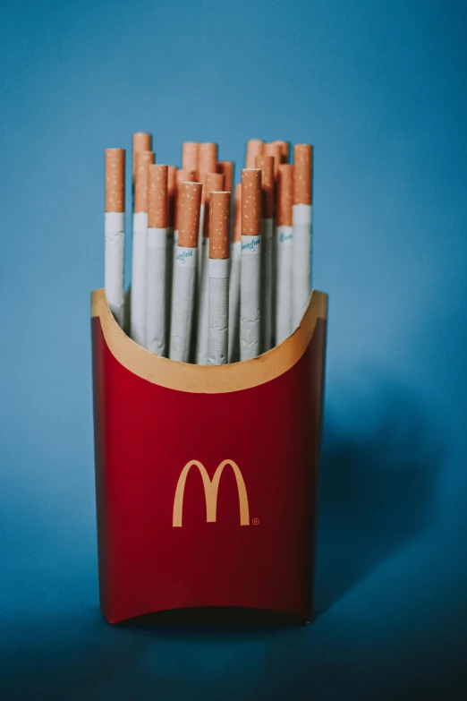 a red box filled with cigarettes on top of a blue background, by Mac Conner, unsplash, hyperrealism, mcdonalds interior background, stems, (smoke), golden arches