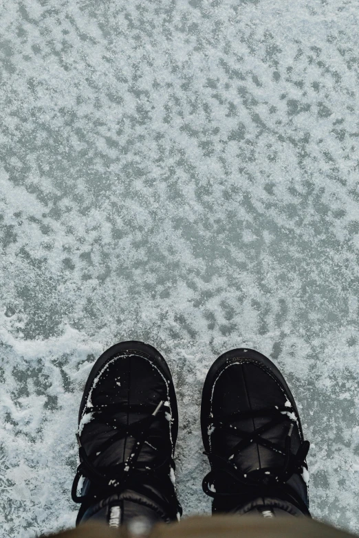 a person standing on top of a snow covered ground, trending on pexels, black shoes, ice fish shape, white, black