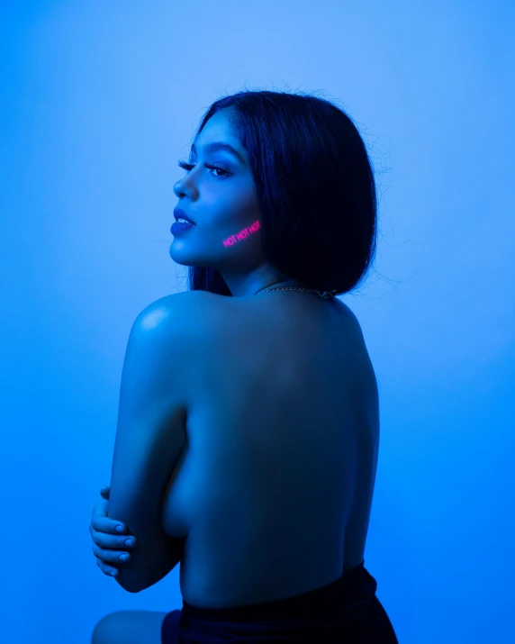 a naked woman sitting in front of a blue background, an album cover, trending on pexels, holography, blue and red lights, madison beer, profile image, neon cybernetic implants