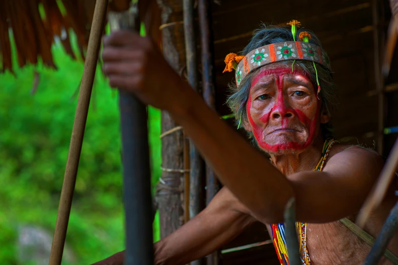 a man that has some paint on his face, by Dietmar Damerau, pexels contest winner, sumatraism, holding a bow and arrow, avatar image, an old lady with red skin, thumbnail