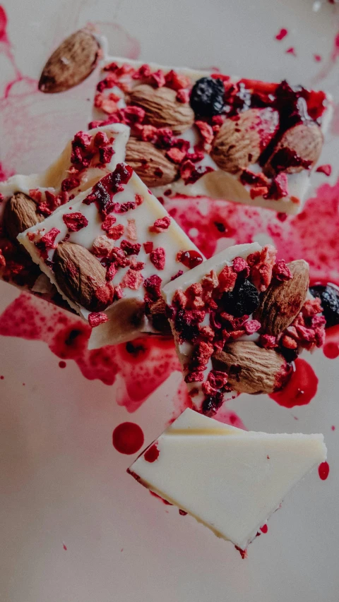 a piece of cake sitting on top of a white plate, by Lee Loughridge, pexels, renaissance, candy decorations, maroon red, nut, squashed berries