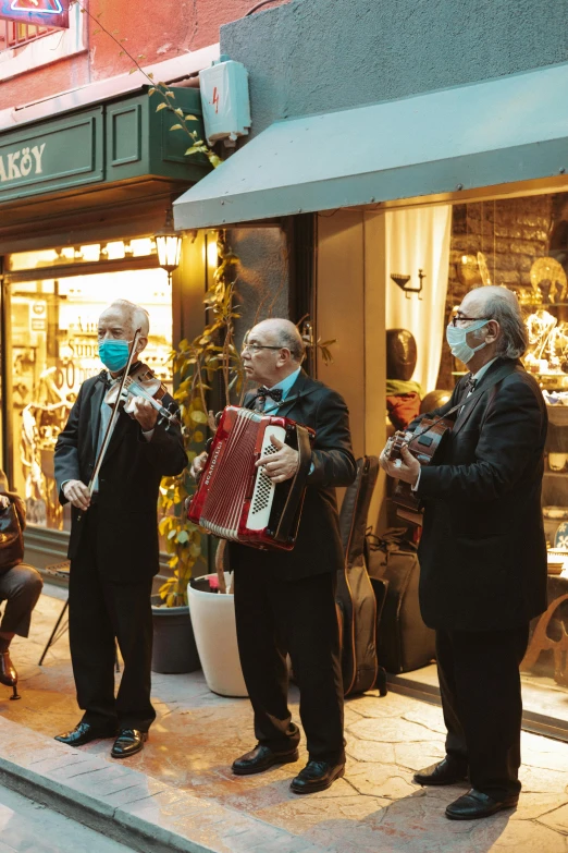 a group of people that are standing in the street, an album cover, pexels contest winner, baroque, old man doing with mask, trio, warm street lights store front, an instrument