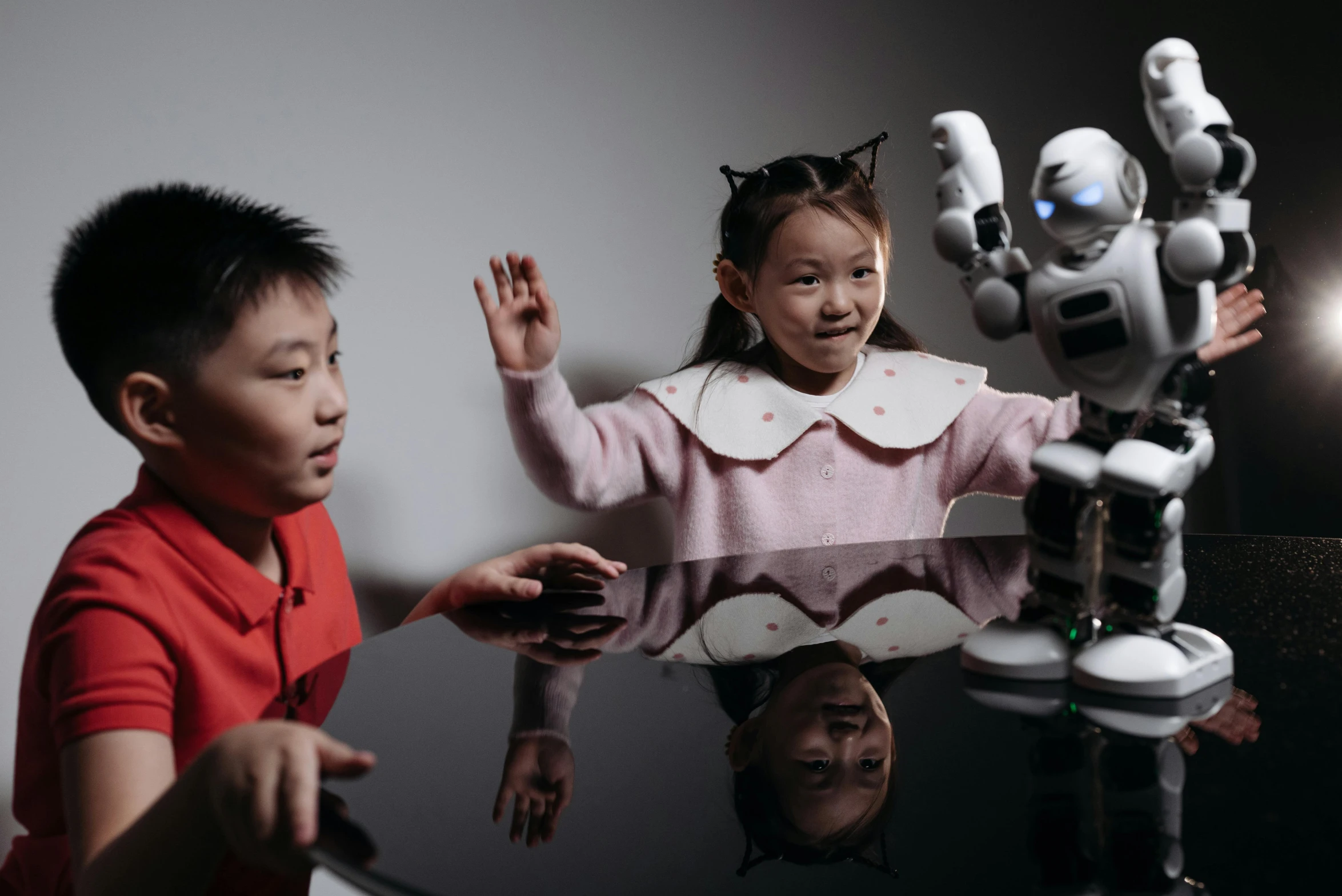 a couple of kids sitting at a table with a robot, a portrait, pexels contest winner, interactive art, chinese, waving, 15081959 21121991 01012000 4k, three point lighting bjork