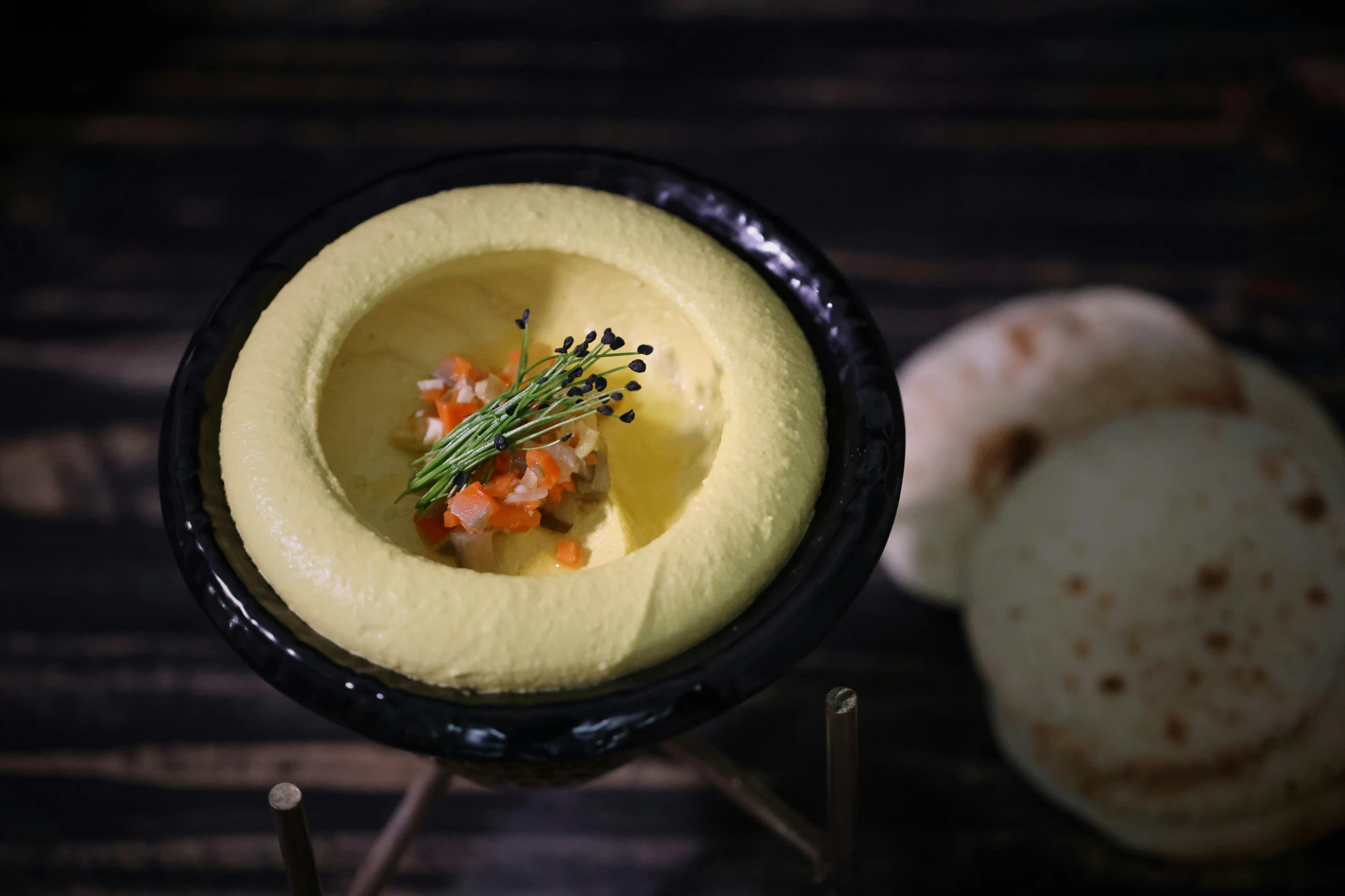 a close up of a bowl of food on a table, a pastel, inspired by Ceferí Olivé, unsplash, hurufiyya, made of cheese, humus, nighttime, server in the middle