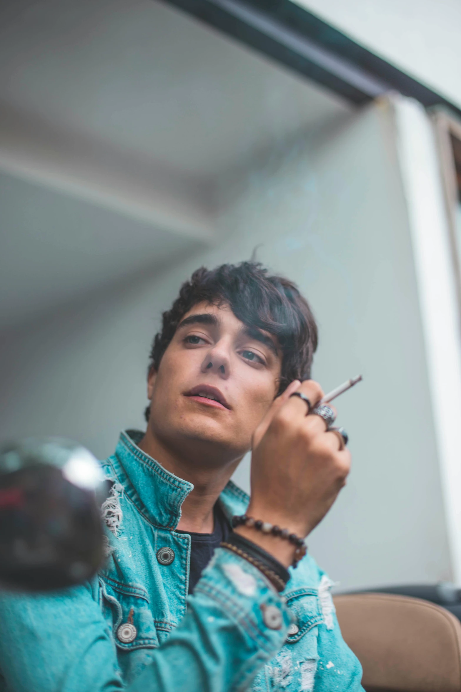 a man sitting in a chair talking on a cell phone, an album cover, inspired by Luca Zontini, trending on pexels, beautiful androgynous girl, smoking a joint, headshot profile picture, riccardo scamarcio