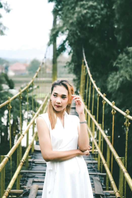 a woman in a white dress standing on a bridge, inspired by Ina Wong, pexels contest winner, sumatraism, handsome girl, gold, white backround, laos