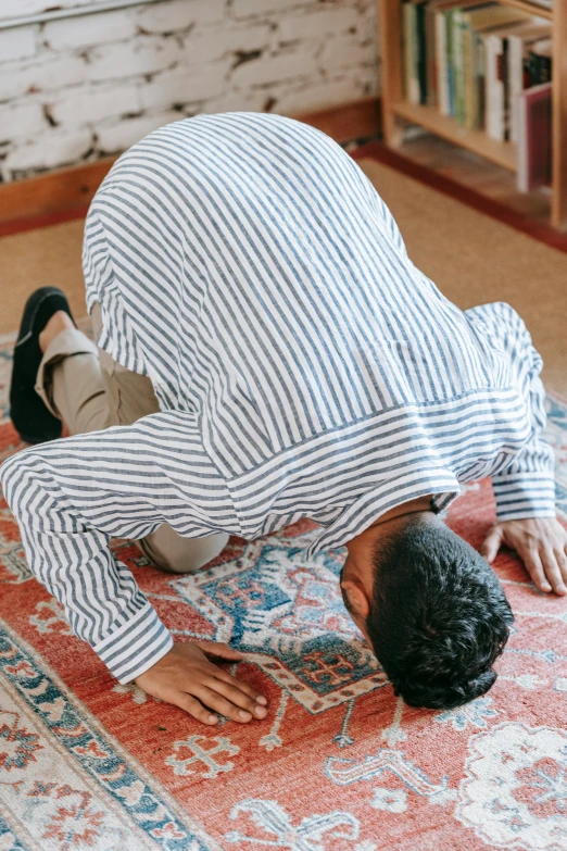 a man bending over on a rug in a living room, pexels contest winner, hurufiyya, praying posture, 64x64, patterned, dynamic moving pose