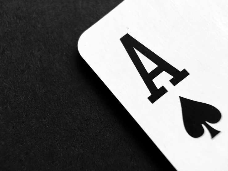 a playing card sitting on top of a table, a black and white photo, unsplash, ace card, profile picture 1024px, letter a, online casino logo