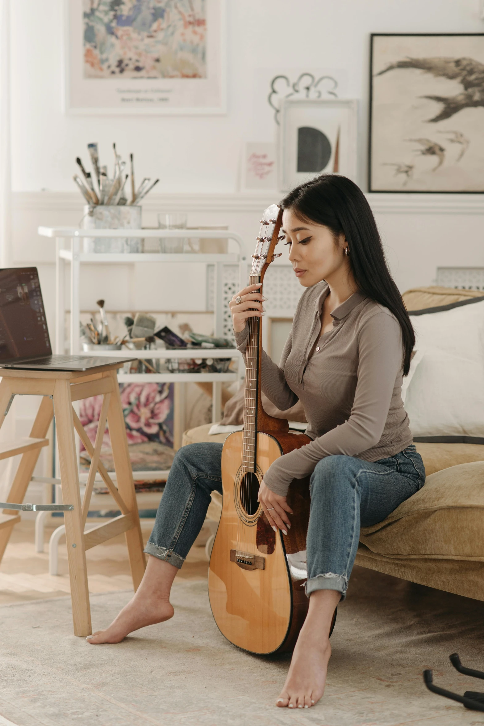 a woman sitting on a couch playing a guitar, inspired by Song Xu, trending on pexels, stands at her easel, profile pic, promo image, leaked photo