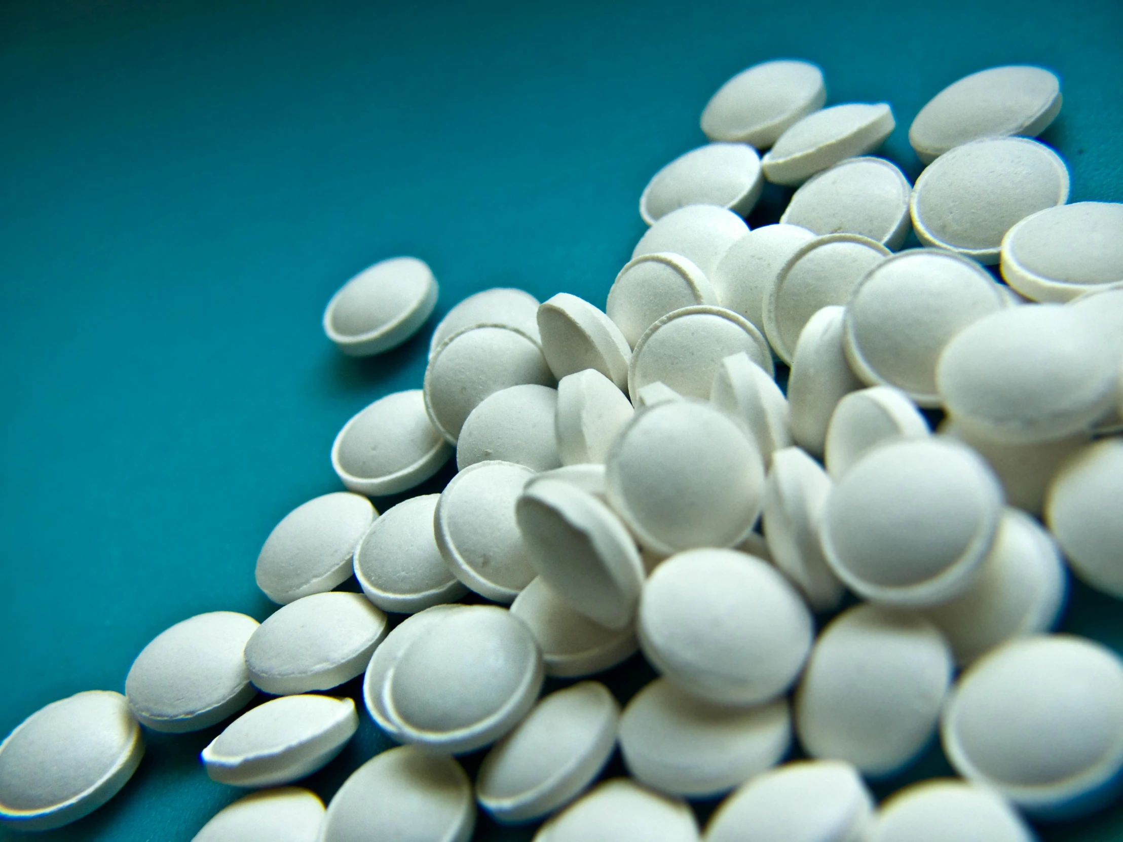 a pile of white pills sitting on top of a blue table, inspired by Vija Celmins, unsplash, plasticien, emeralds, round-cropped, white coat, 1 9 2 0's