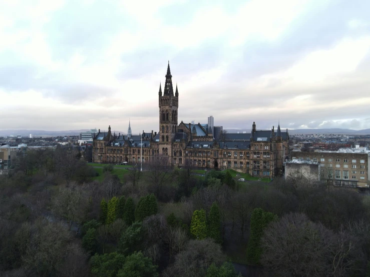 a large building sitting on top of a lush green field, by John Murdoch, pexels contest winner, academic art, glasgow in background, 🎀 🧟 🍓 🧚, wide high angle view, gothic aesthetic