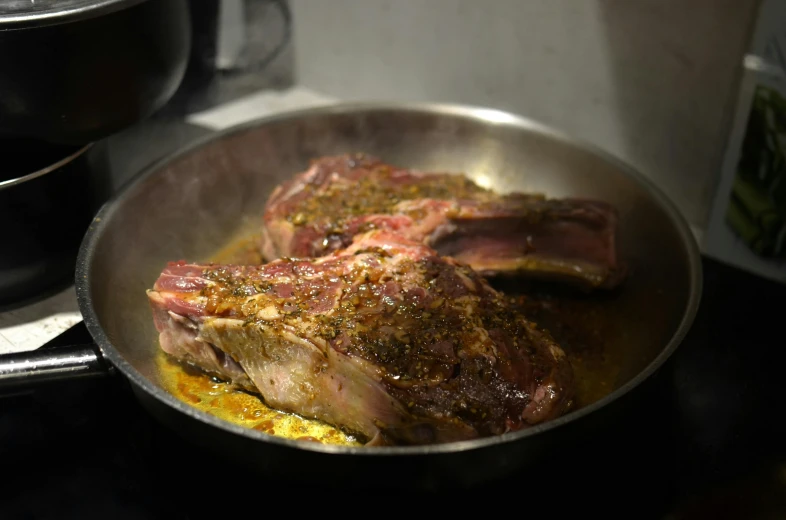a pan filled with meat sitting on top of a stove, les nabis, mutton chops, ignant, angled shot, herbs
