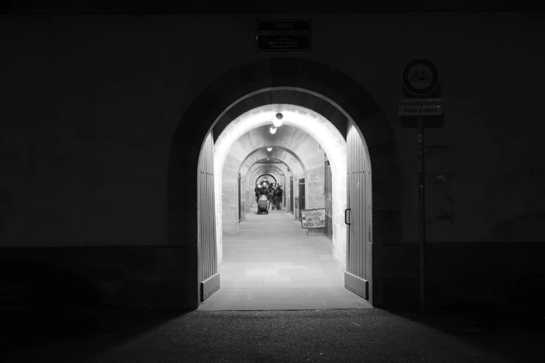 a black and white photo of a light at the end of a tunnel, a black and white photo, by Kristian Zahrtmann, pexels, conceptual art, grossmünster, people at night, pink arches, lock