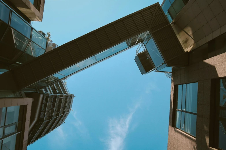 a couple of buildings that are next to each other, inspired by Richard Wilson, pexels contest winner, modular constructivism, sky bridge, sky blue, opposite the lift-shaft, view from ground