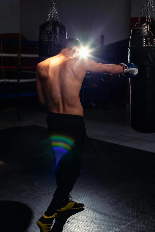 a man standing next to a punching bag, a hologram, by Tom Bonson, pexels contest winner, happening, back - shot, six-pack, david marquez, instagram picture