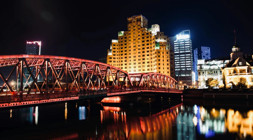 a bridge over a body of water at night, by Zha Shibiao, pexels contest winner, art nouveau, red - yellow - blue building, shanghai, slide show, square