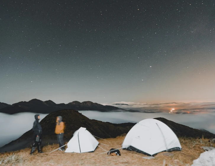 a couple of people standing on top of a mountain, trending on unsplash, tents, set at night, high quality photo, profile image