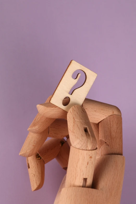 a person holding a piece of wood with a question mark on it, an abstract sculpture, trending on pexels, purple, toys, diecut, etsy