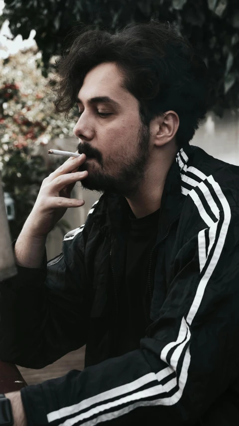 a man sitting on a bench smoking a cigarette, an album cover, inspired by Enrique Tábara, unsplash contest winner, profile image, wearing a track suit, goatee, ray william johnson