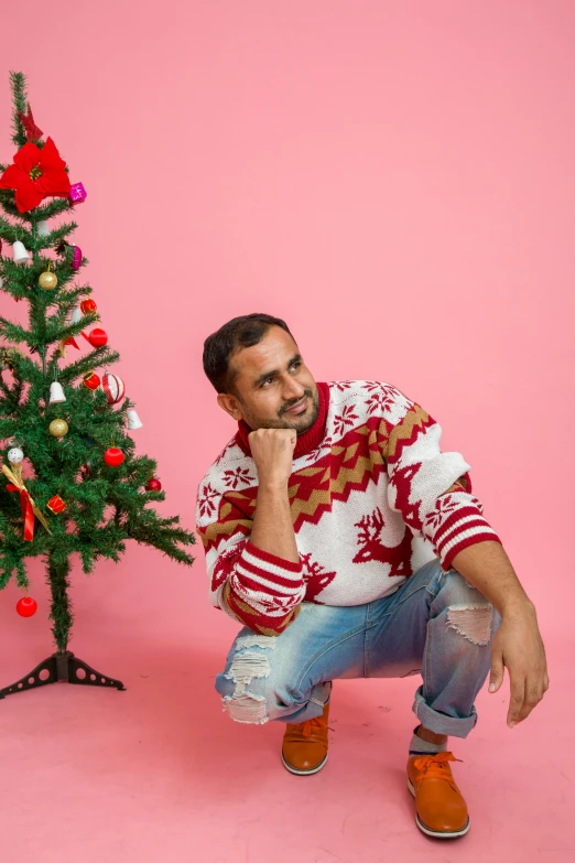 a man kneeling in front of a christmas tree, an album cover, pexels contest winner, wearing a kurta, sweater, solid background, avatar image