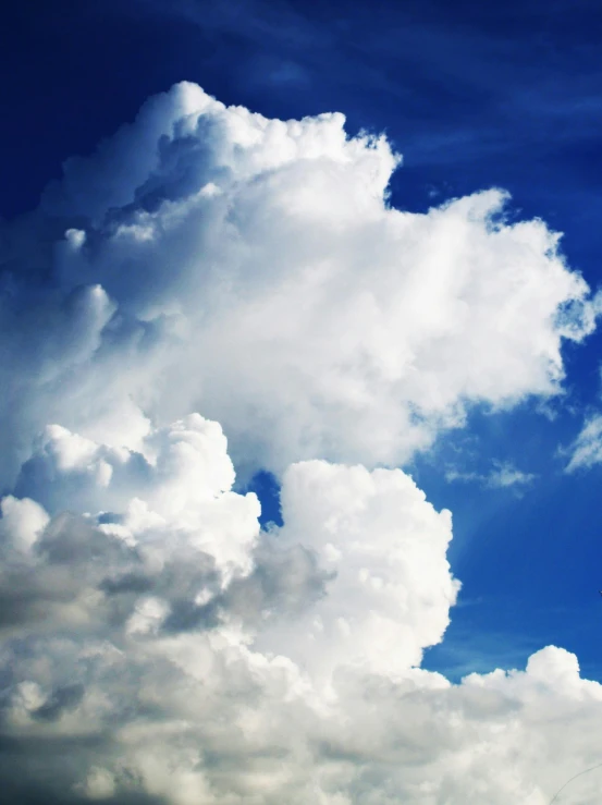 a plane flying through a cloudy blue sky, unsplash, towering cumulonimbus clouds, avatar image