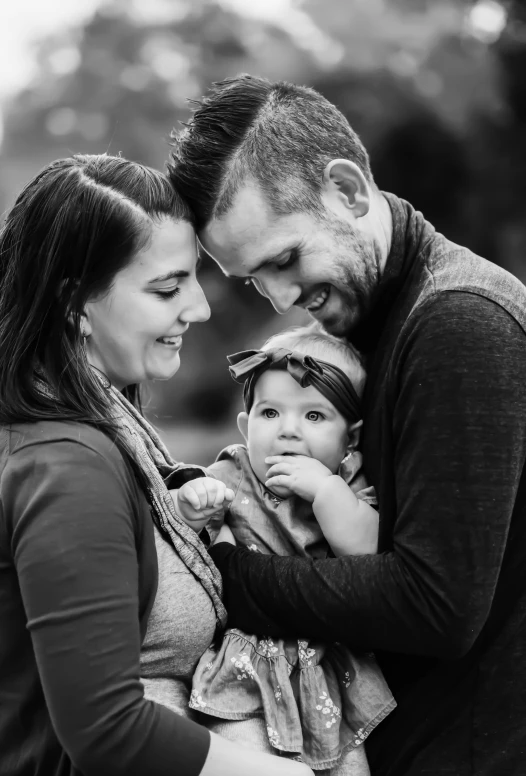 a black and white photo of a man and woman holding a baby, a black and white photo, by Chris Rallis, pexels contest winner, smiles and colors, square, fall, headshot profile picture