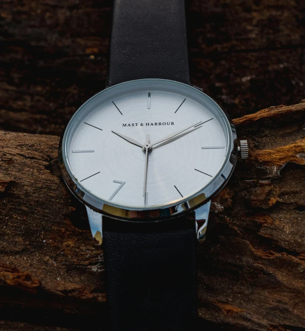 a watch sitting on top of a piece of wood, by Carey Morris, minimalism, black draconic - leather, white: 0.5, close up image, thumbnail