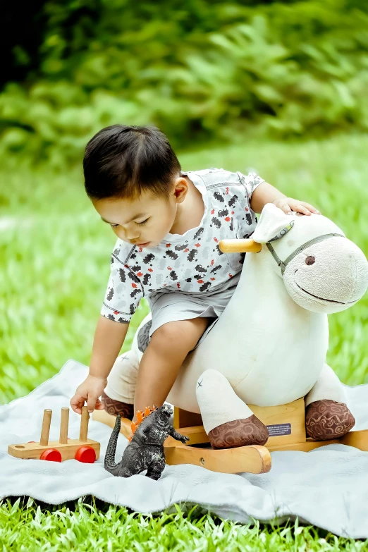 a little boy that is sitting on a toy horse, inspired by Abidin Dino, blue'snappy gifts'plush doll, jakarta, vignette, in garden