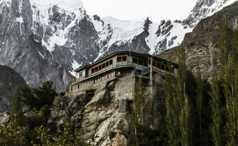 a large building sitting on top of a mountain, hurufiyya, rocky cliff, snow capped mountains, restaurant, lpoty