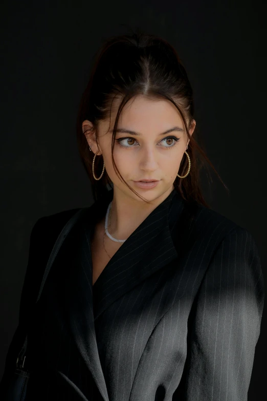 a woman in a suit posing for a picture, inspired by Emma Andijewska, trending on pexels, photorealism, hoop earrings, portrait sophie mudd, teenager girl, 7 0 mm dramatic lighting